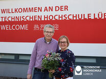 TH Lübeck Präsidentin steht mit Blumenstrauß neben Senatsvorsitzenden