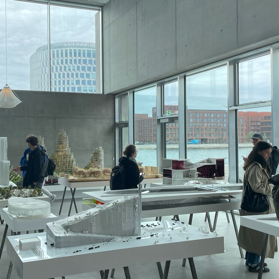 Studierende gucken sich Modellhäuser in einer Halle an