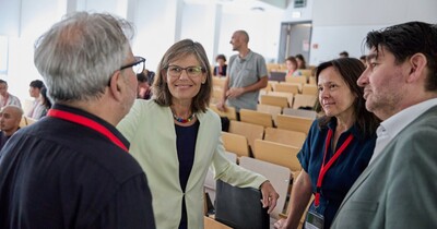 Vier Menschen stehen in einem Hörsaal zu einem Gespräch zusammen.