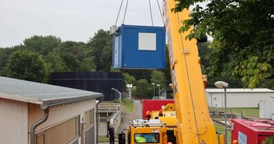 Der blaue Container wird von dem Kran angehoben