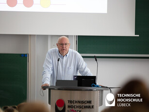 Dankesrede der Rose Stiftung Ein Mann steht an einem Rednerput in einem Hörsaal