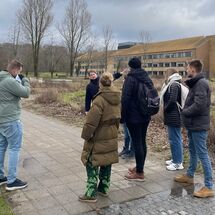 5 Personen stehen um einer sechsten herum die etwas erklärt