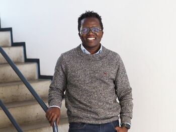 Lächelnder Mann mit Brille steht angelehnt an Treppengeläner