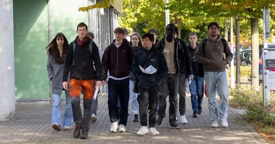 Eine Gruppe junger Menschen läuft über den Campus.