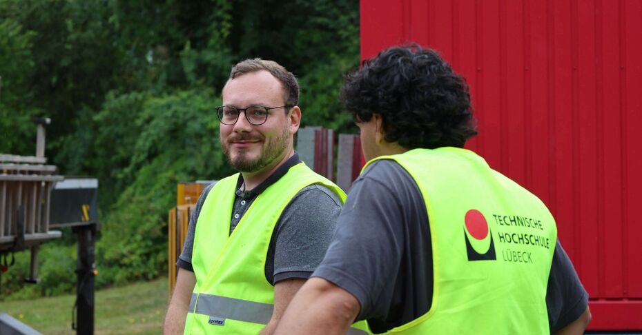 Zwei Studenten vor einem roten Container