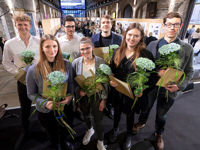 Bild zeigt 7 Personen mit Urkunden und Blumensträußen in den Händen