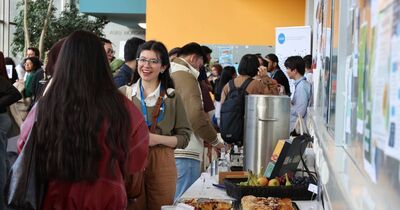Eine junge Frau steht neben einem Kuchenbuffet und unterhält sich.