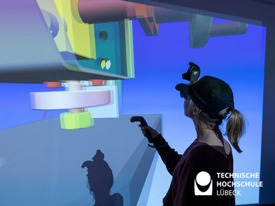 Frau mit AR Brille und Joystick steht vor einer Leinwand