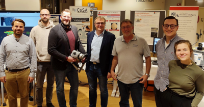 Ein Gruppenfoto von  Männern und einer Frau bei einer Ausstellung