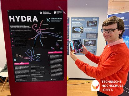 Immersive Medien Person steht neben ein Augmented Reality Poster und scannt es mit dem Tablet