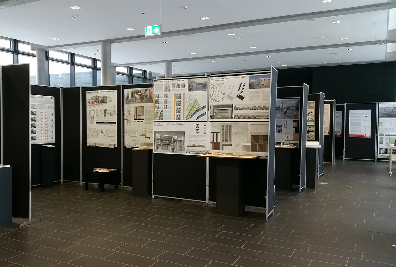 Architektur-Ausstellung: Stellwände mit Plänen und Modelle auf Podesten.