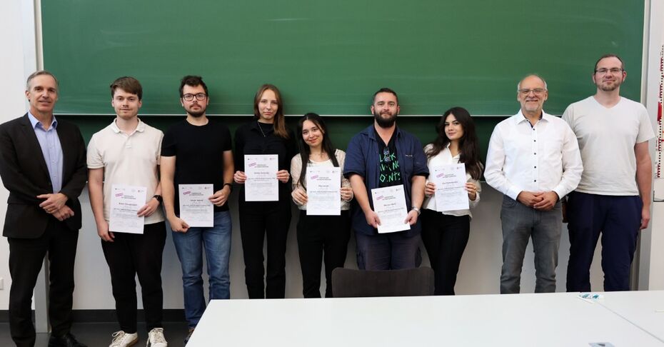 Ein Team steht mit den Organisatoren und Zertifikaten in den Händen vor einer grünen Tafel