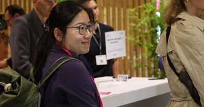 Eine junge Frau lächelt und steht an einem Tisch.
