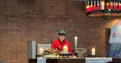 Eine Frau steht an einem Altar, auf dem Kerzen stehen und liest vor