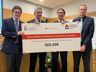 Four men hold up a large check for an economics prize for the camera.