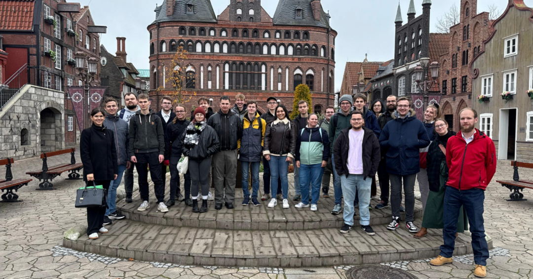 Gruppe posiert auf einem Platz vor historischen Backsteingebäuden.