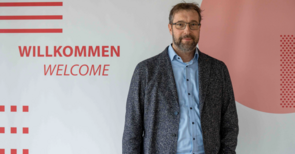 Prof. Dr. Kai Wellbrock steht vor einer Wand mit dem Schriftzug Willkommen.