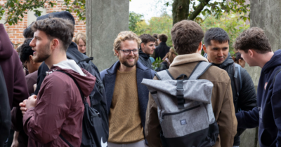 Junge Männer stehen draußen in Grüppchen zusammen.