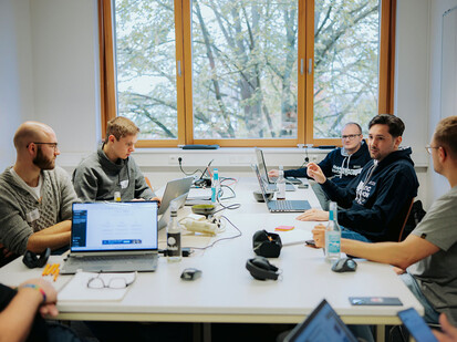 Team Greifswald bei der Arbeit Mehrere Personen sitzen an einem Tisch und arbeiten an Laptops