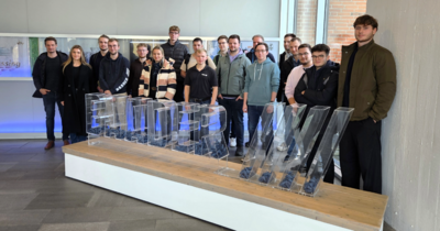 Besuchergruppe steht hinter einem großen transparenten BAADER-Schriftzug.