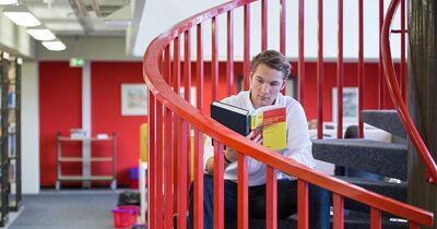 Ein Student sitzt auf einer Treppe und liest.