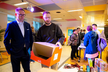 Bürgermeister Lübecks im Gespräch mit Ausstellern Aussteller hält Karton in Hand und erklärt dem Bürgermeister etwas