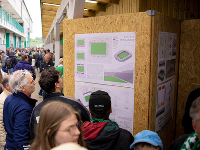 Viele Personen stehen vor einem Plakat