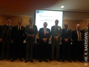 Group photo of several men in suits in front of a presentation screen.