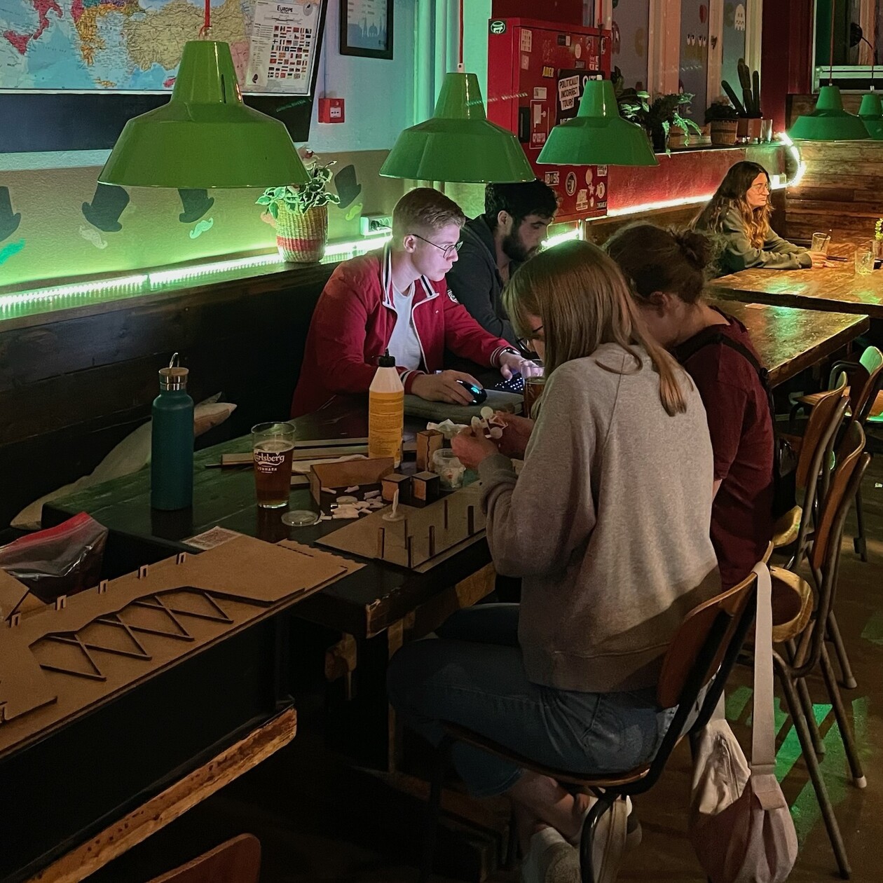Teilnehmende Zwei Personen sitzen in einer Bar mit grünem Licht an einem Tisch