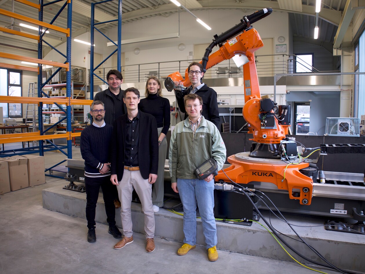 6 Personen stehen vor einem Industrieroboterarm