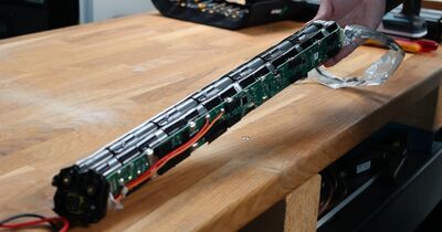 Auf einer Werkbank liegt eine geöffnete Fahrradbatterie. 