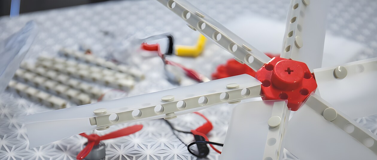 Close-up of a self-built model of a wind turbine with batteries and cables on a table.