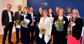 Mehrere Menschen stehen zusammen und halten Blumensträuße in der Hand.