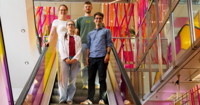 4 Menschen auf einem Bild die die Rolltreppe herunterfahren 