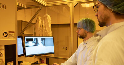 Die Doktoranden Gregor Knoll (r.) und Fabian Henk stehen vor einem Bildschirm und überwachen den Druckprozess.