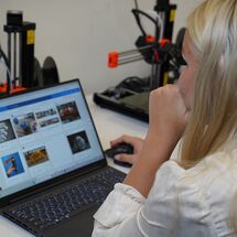 Frau sitzt am Laptop und guckt nach 3d Druckteilen