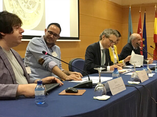 A close-up view of five speakers seated at a panel discussion table.