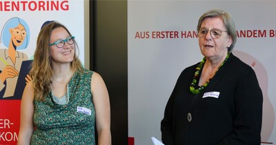Zwei Frauen stehen nebeneinander und halten einen Vortrag.