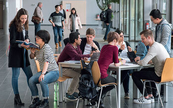 Internationale Studierende studieren gemeinsam an einem Tisch im Audimax der TH Lübeck