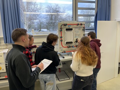 Messung Strömungslehre Fünf Studierende stehen an einer Wand mit Rohren und messen