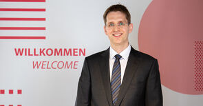 Auf dem Bild steht der neue Professor des Fachbereichs Maschinenbau und Wirtschaft, Dr.-Ing. David Kuhlen, vor einem Banner der Technischen Hochschule.