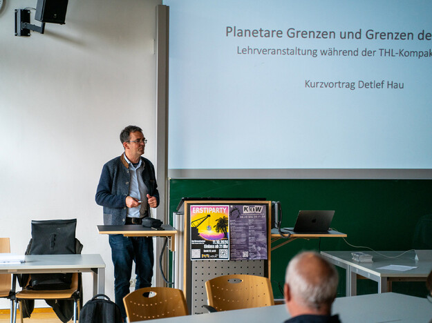 Best Practice Beispiele zur nachhaltigen Entwicklung Mann steht am Rednerpult und im Hintergrund eine Leinwand
