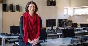 Eine Frau sitzt in einem PC-Raum auf einem Tisch.