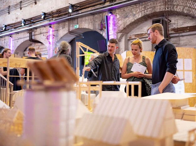 Im Fokus drei Personen die sich Ausstellungsobjekt angucken