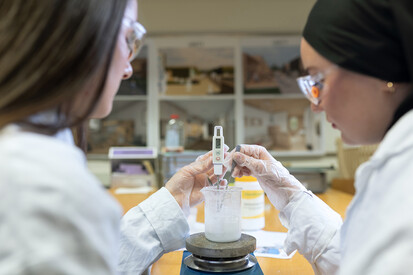 Studierende Zwei Personen halten Messgeräte in ein Glas