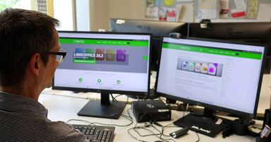 Ein Mann sitzt vor zwei Bildschirmen, auf denen LibreOffice läuft
