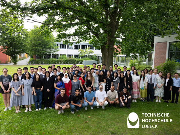 Abschlussbild der international Studierenden Studierende stehen im grünen und lächeln