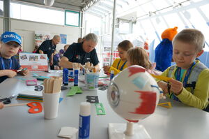 Kinder basteln und experimentieren am Tisch mit verschiedenen Alltagsmaterialien