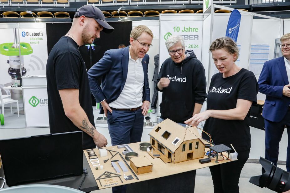 Drei Personen erklären einer vierten anhand eines Modells etwas