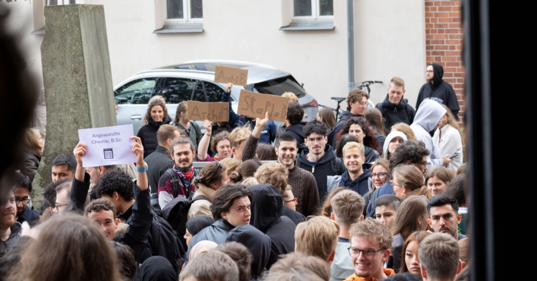 Junge Menschen halten Schilder mit ihren Studiengängen hoch.